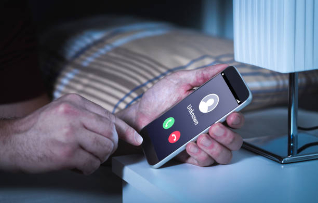 Unknown number calling in the middle of the night. Phone call from stranger. Person holding mobile and smartphone in bedroom bed home late. Unexpected call woke up.