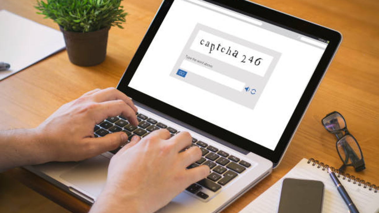 Close-up top view of a man writing captcha code on laptop. all screen graphics are made up.