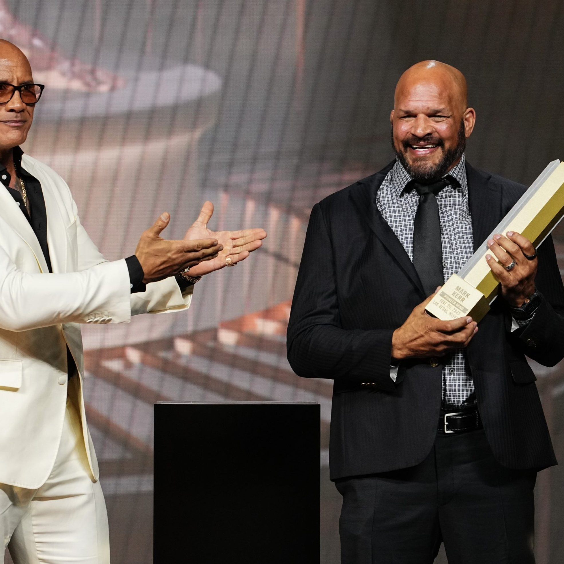 LAS VEGAS, NEVADA - JUNE 26: (L-R) Dwayne Johnson presents the UFC Hall of Fame trophy to Mark Kerr during the UFC Hall of Fame Class of 2025 Induction Ceremony at T-Mobile Arena on June 26, 2025 in Las Vegas, Nevada. (Photo by Jeff Bottari/Zuffa LLC)